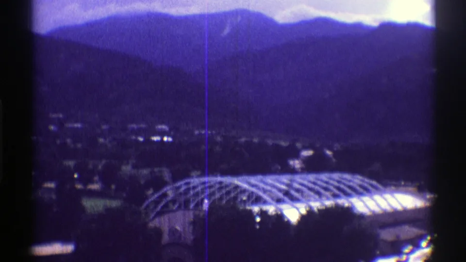 The final 1969 Colorado frame centers more of the arched greenhouse roof, with a mountain village, trees, and layered ridges in the background.
