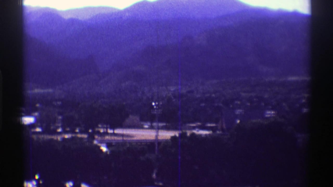 Distant mountain ridge and valley settlement seen through a dark vertical frame divider.