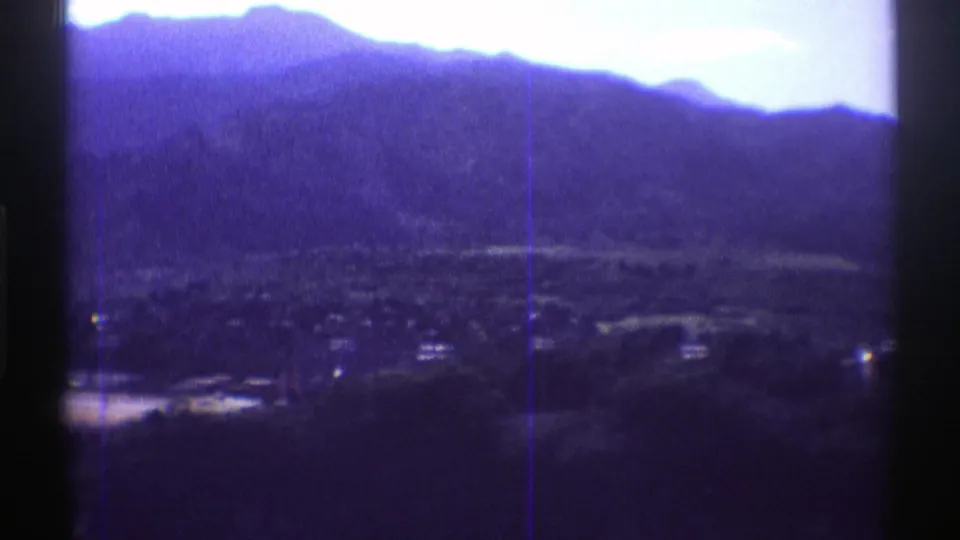 1969 Colorado mountain-valley panorama on 8mm film, showing scattered settlement details beneath a blue-purple ridge line.