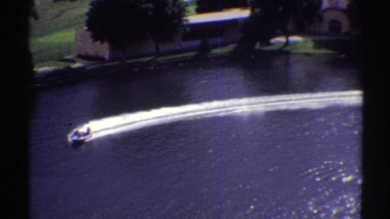 Speedboat begins a curved turn on the lake with a long bright wake trailing behind.