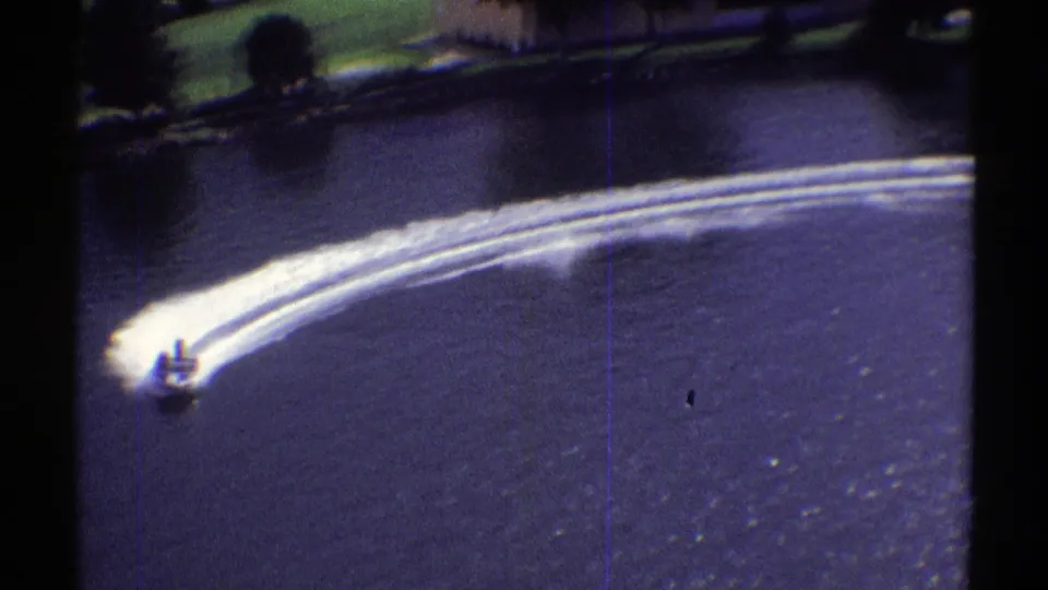 A small speedboat in the 1969 Colorado footage cuts a sharper turn, with foamy wake lines spreading across the lake.