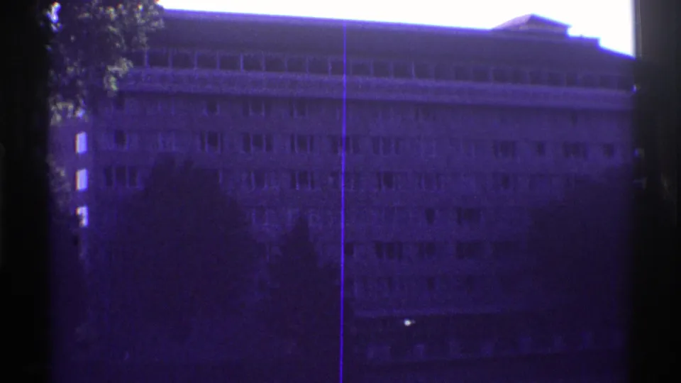 1969 Colorado 8mm frame of a shaded multi-story building with rows of windows and visible film gate edges.