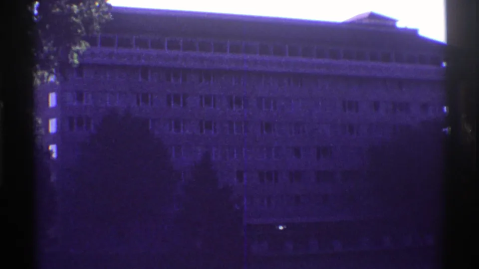 1969 Colorado home-movie frame showing the building exterior again, softened by grain and a purple film cast.