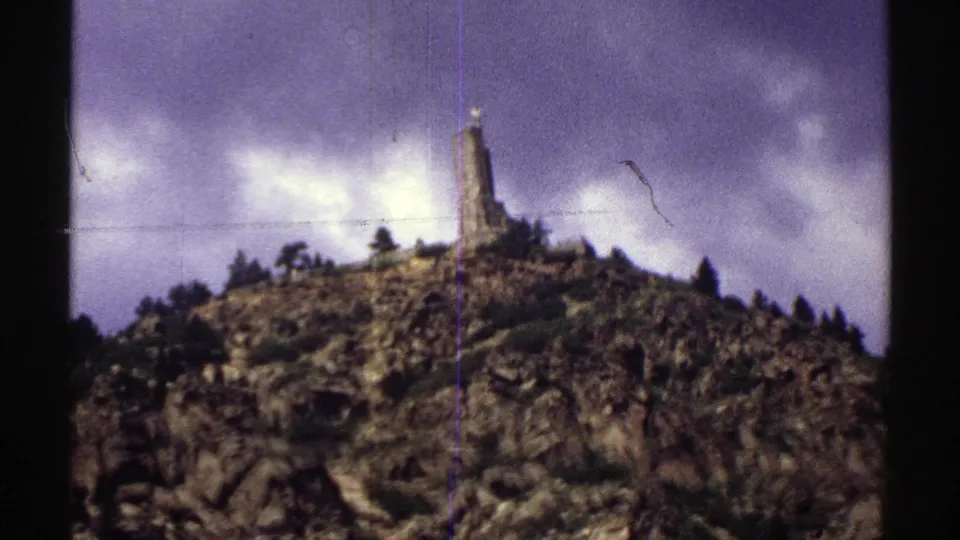 1969 Colorado 8mm frame with a closer view of the stone monument, rocky ground, trees, and visible film scratches.