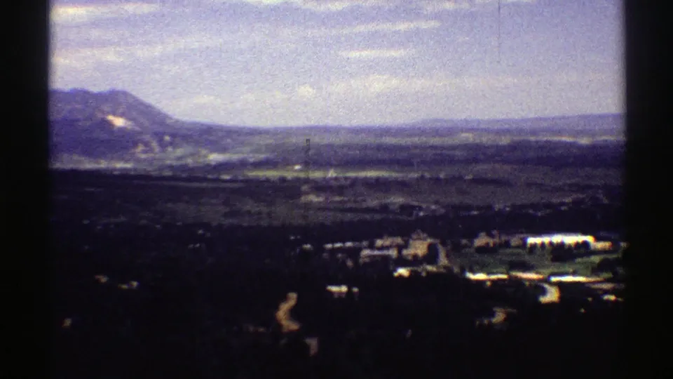 1969 Colorado 8mm frame looking across a valley with distant hills, roads, and small structures below.