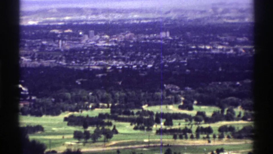 1969 Colorado 8mm frame showing a golf course in the foreground and a hazy suburban town beyond.