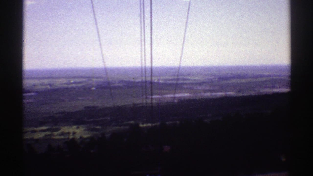 Distant outdoor landscape seen through dark film-frame edges and vertical scratches.