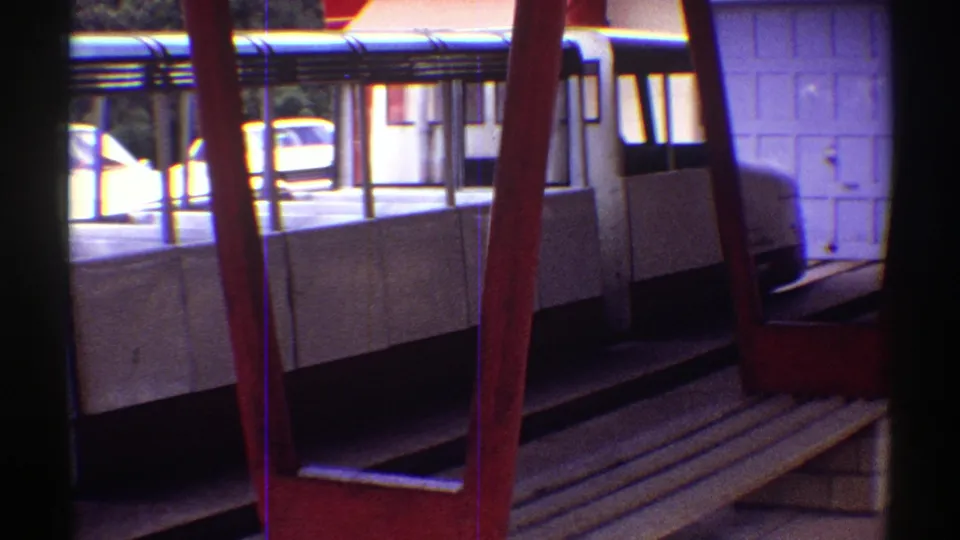 1969 Colorado home-movie frame showing a white tour vehicle or tram area with red railings and empty bench seating.