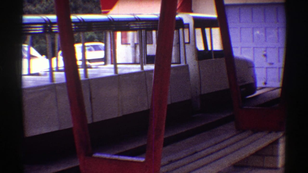 White-draped benches under an open shelter with red posts and a parked car beyond.