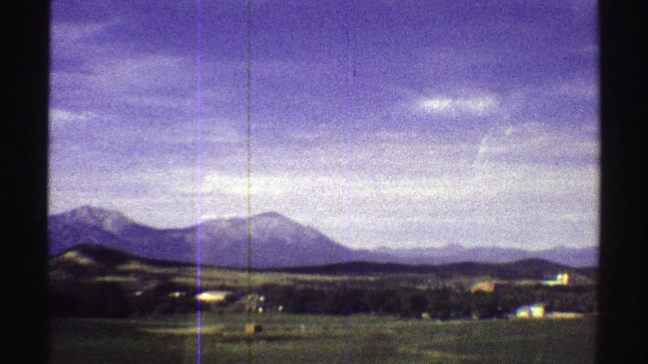 Distant mountains and open plains under a blue-purple sky with film gate edges.