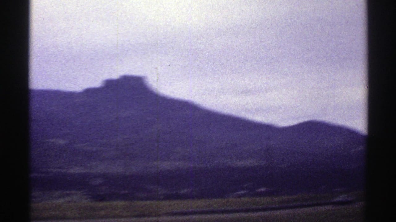 1969 Colorado 8mm frame with the mountain ridge filling more of the view, a soft foreground, and overcast sky.