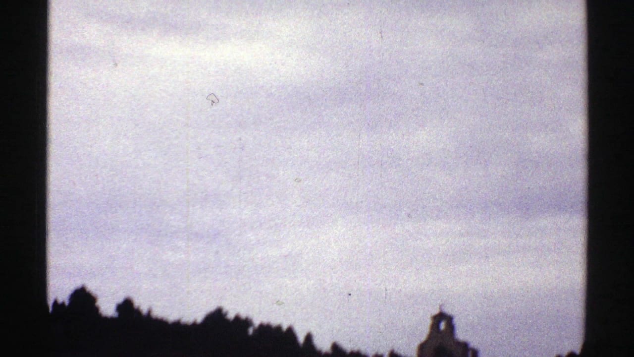 Cloudy sky and dark ridge divided by a vertical black film-frame edge.
