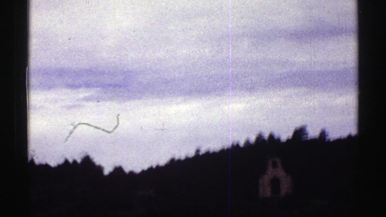 1969 Colorado 8mm road-trip frame showing a windshield view toward dark wooded hills under a pale cloudy sky.