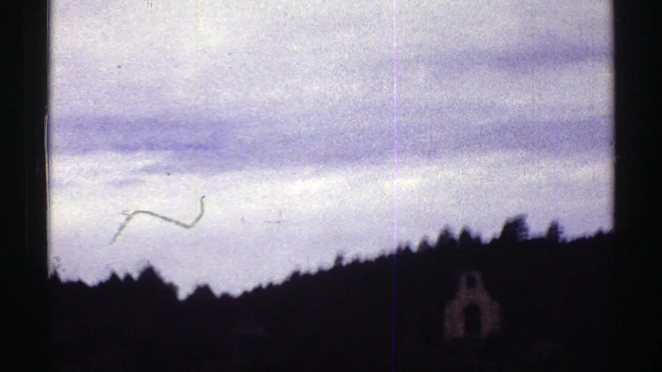 1969 Colorado 8mm road-trip frame showing a windshield view toward dark wooded hills under a pale cloudy sky.