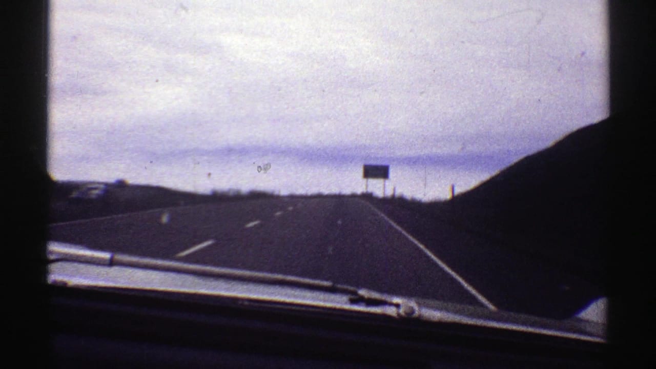 1969 Colorado 8mm car-window view looking down a highway toward a distant green Raton Pass Summit exit sign.