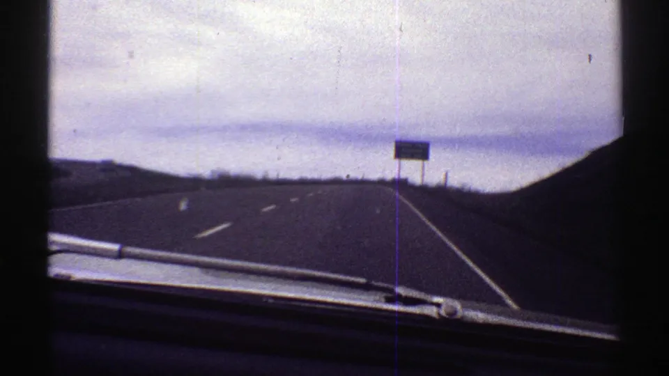 Car POV on a Colorado highway as the Raton Pass Summit next-exit sign grows closer on the right shoulder.