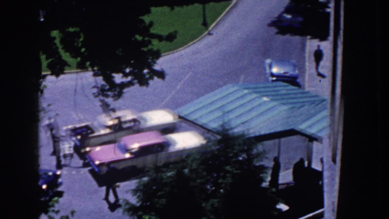 High-angle 1958 view of the French Lick hotel entrance area, with classic cars beside the green canopy and small pedestrian silhouettes.