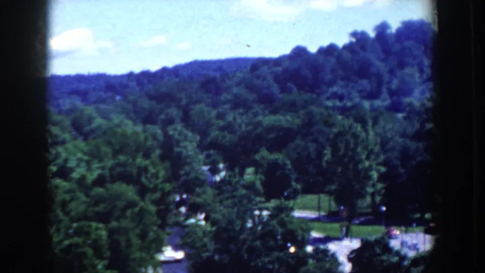 French Lick, Indiana home-movie view of wooded hills, dense trees, and an open green area below.