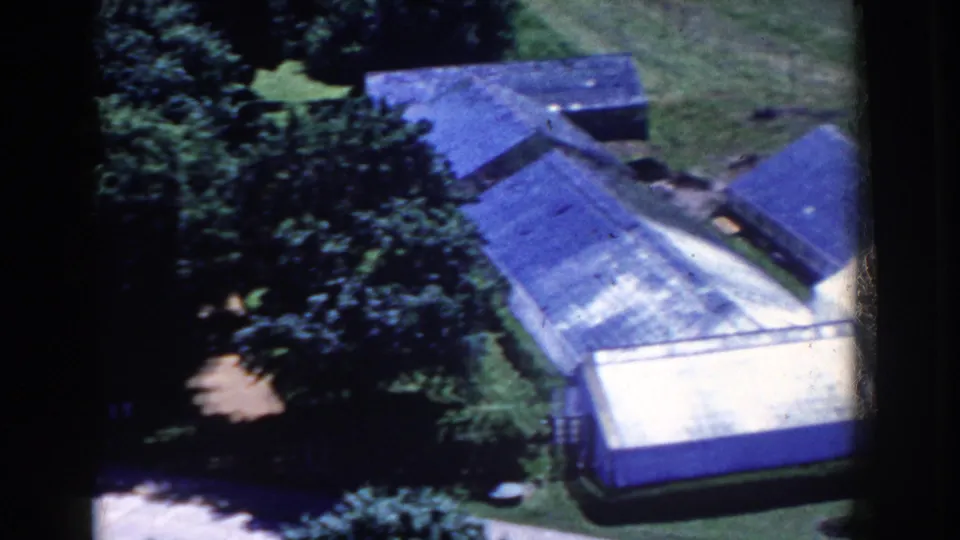 French Lick, Indiana home-movie frame from 1958 showing a large roof, trees, lawn, and a nearby paved strip.