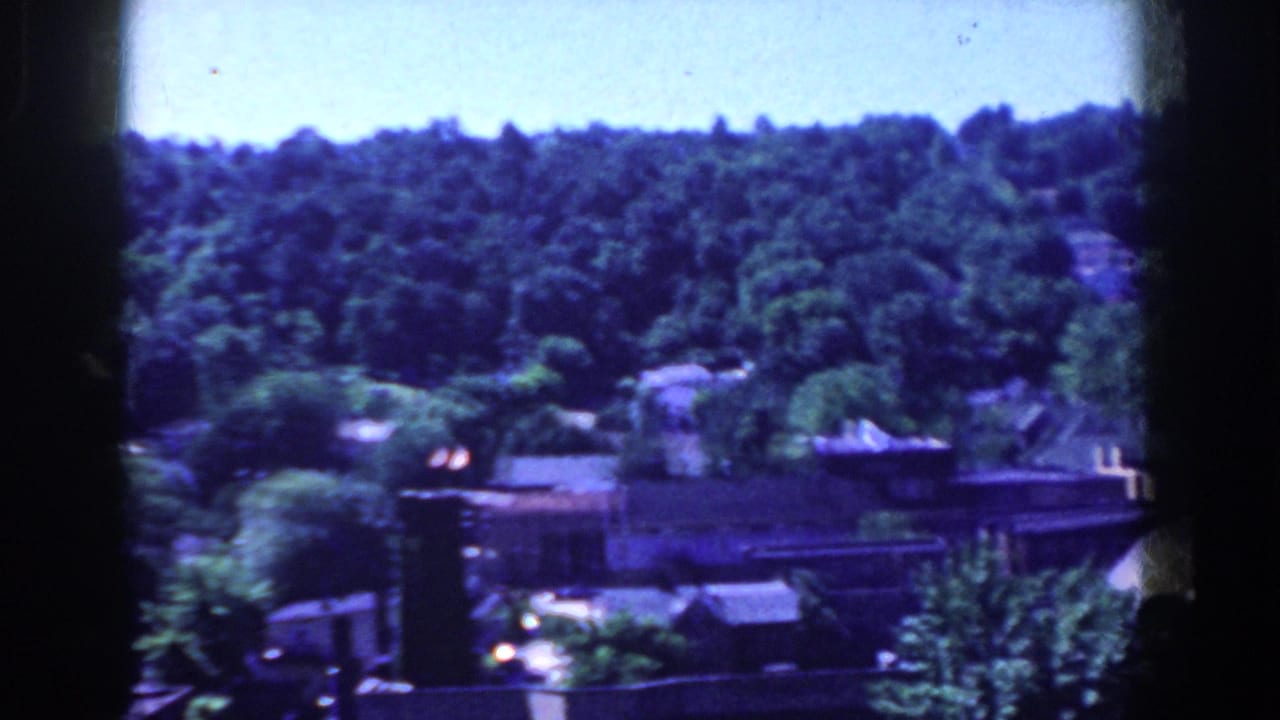 1958 French Lick, Indiana home-movie frame showing trees, rooftops, and a townscape from above.