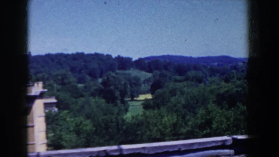 1958 French Lick landscape view showing treetops, open green patches, rolling hills, and a blue sky from an elevated position.