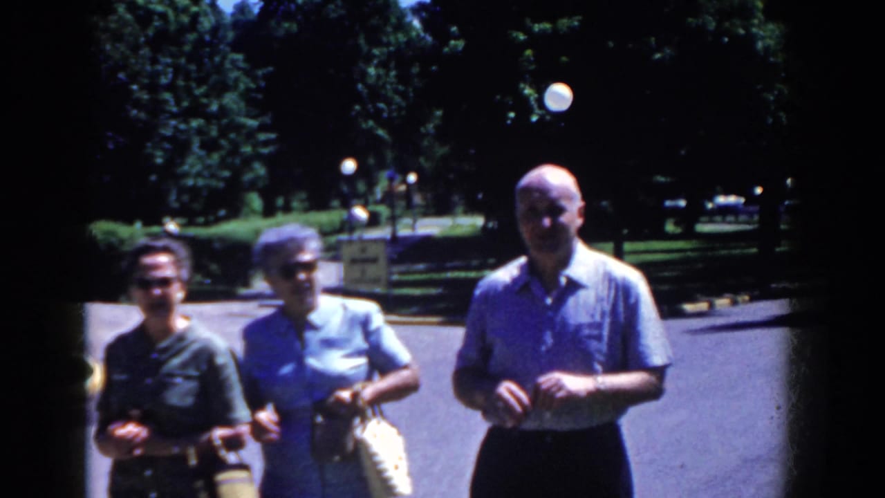 Three adult visitors stand outside in French Lick, Indiana, in a 1958 8mm home-movie frame before the hotel sign views.