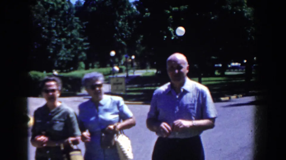 Three adult visitors stand outside in French Lick, Indiana, in a 1958 8mm home-movie frame before the hotel sign views.