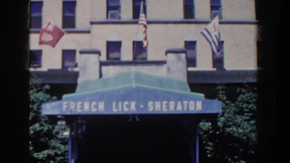 Blue French Lick-Sheraton awning and flags appear against the beige hotel facade in French Lick, Indiana, 1958.