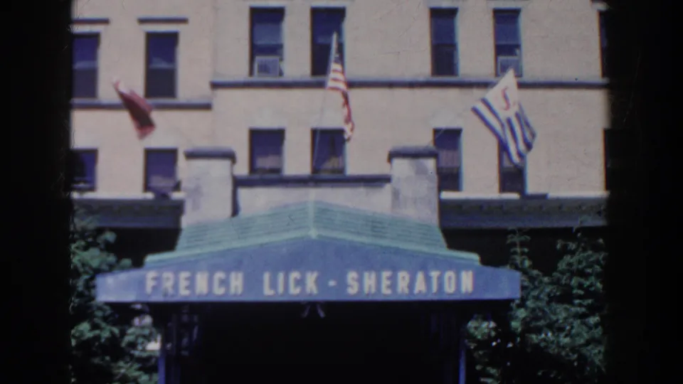 A closer 1958 8mm view shows the French Lick-Sheraton entrance awning, hotel windows, and flags in bright daylight.