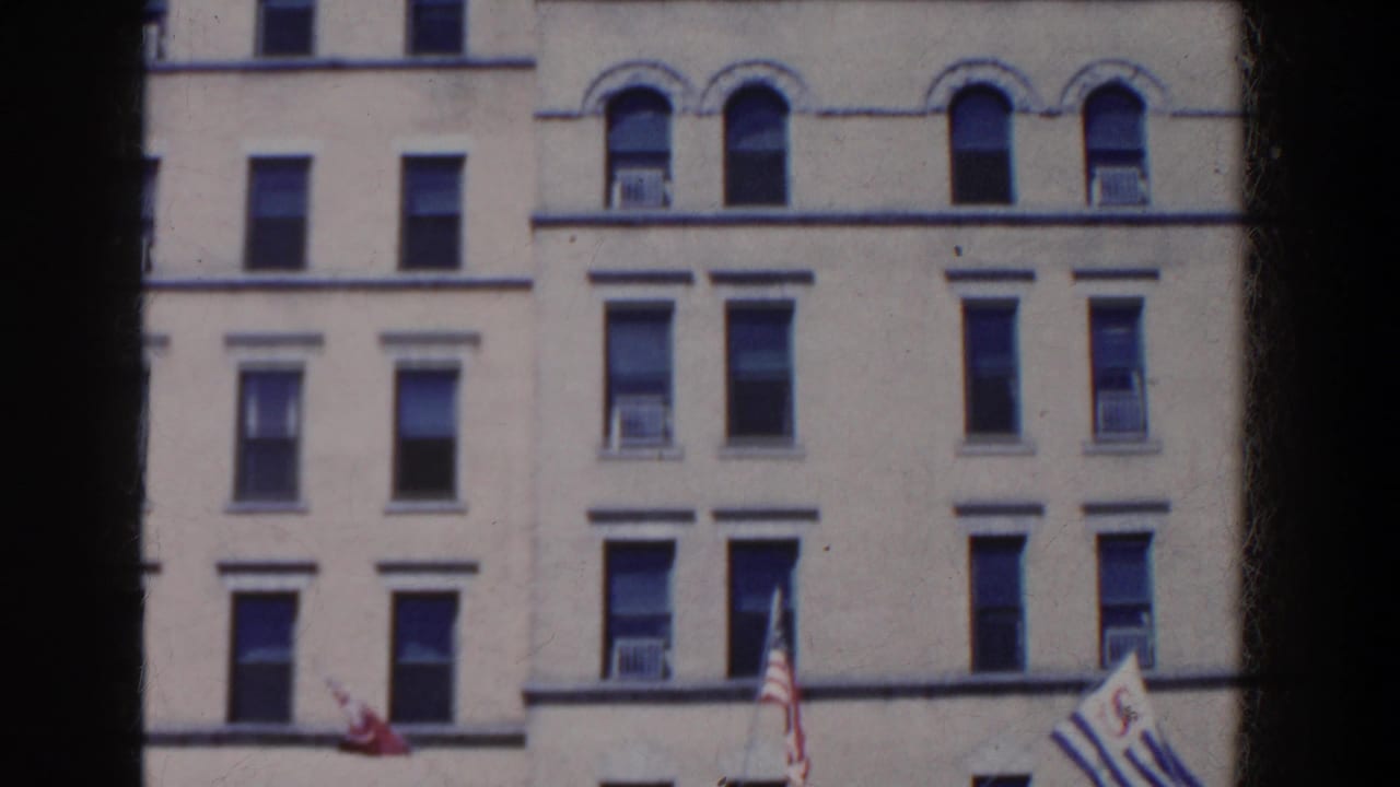 1958 French Lick, Indiana view of a cream building facade with arched windows, air conditioners, and flags partly visible below.