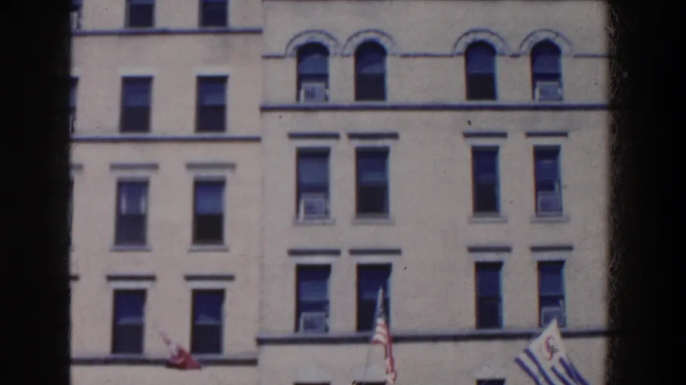 1958 French Lick, Indiana view of a cream building facade with arched windows, air conditioners, and flags partly visible below.