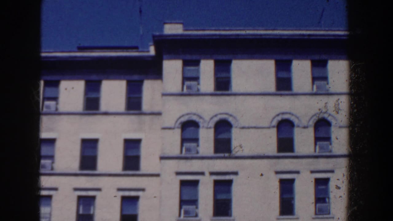Upper stories of a cream building with many windows against a dark blue sky.