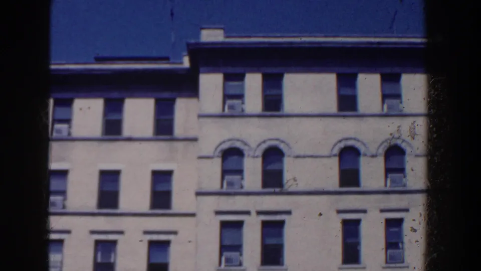 Upper facade of the French Lick building, showing rows of windows, arched details, and rooftop edge against a saturated blue sky.