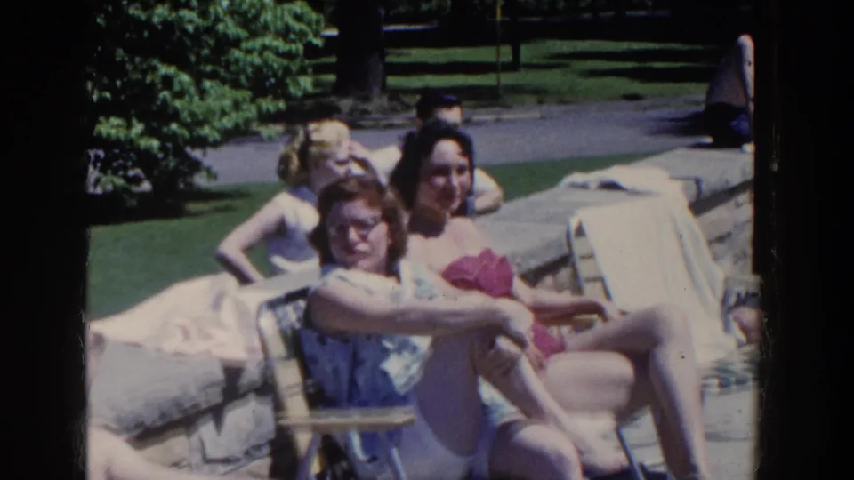 Women in mid-century swimsuits sit and recline on lounge chairs by a private pool in French Lick, Indiana.