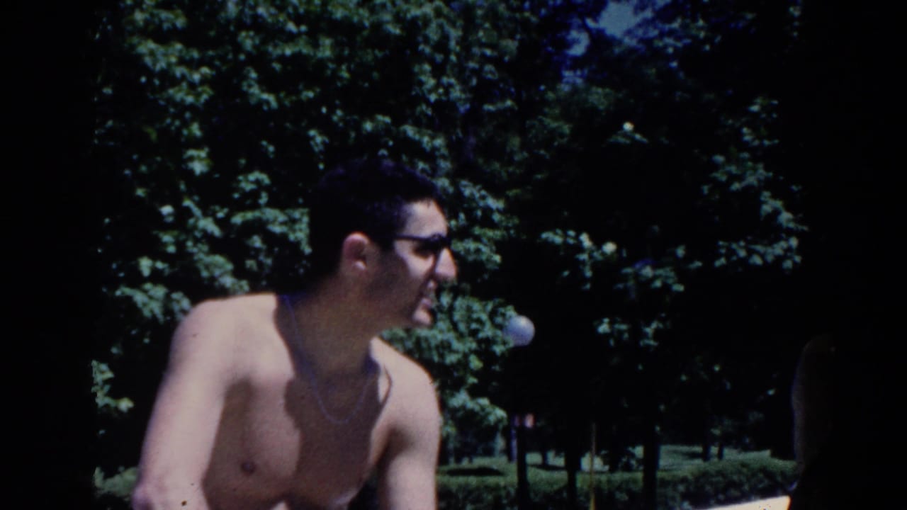 In 1958 French Lick, Indiana, a shirtless man in sunglasses turns near trees during an outdoor resort gathering.