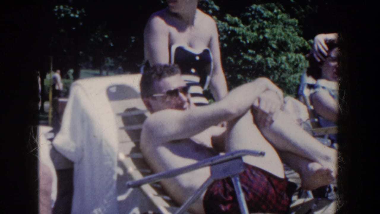 Man in sunglasses lounges on a metal chair beside adults at an outdoor pool.
