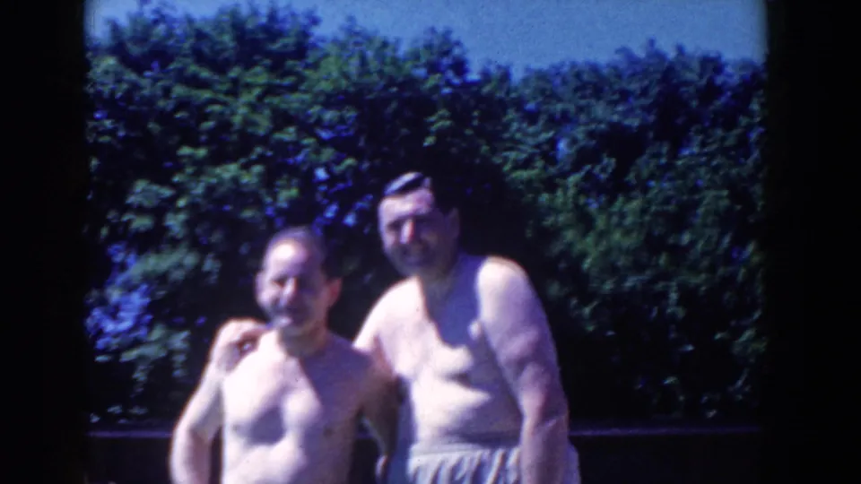 Adults in swimwear stand by the pool in 1958 French Lick, framed softly by handheld 8mm footage and trees.