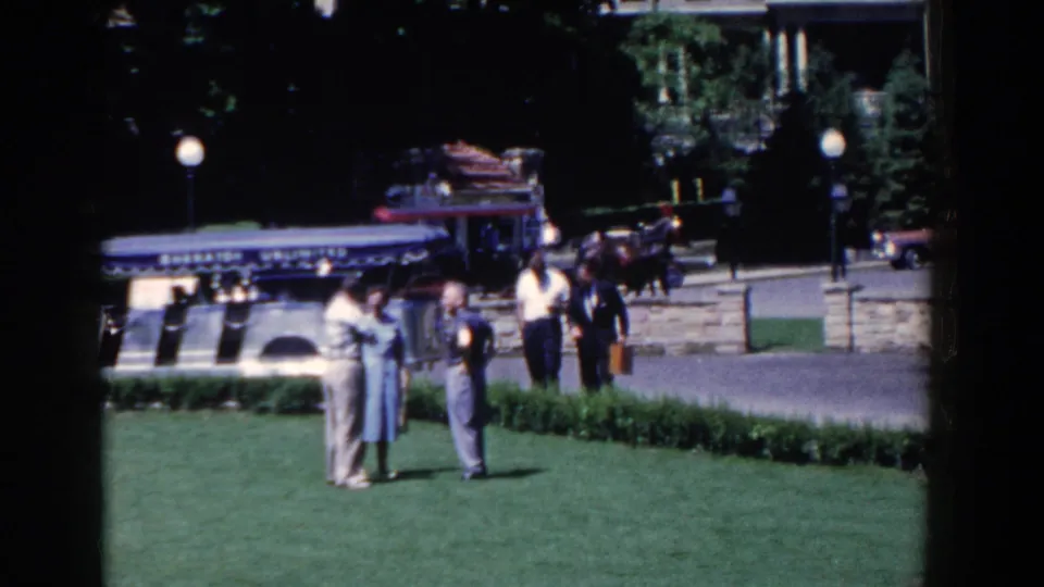 A 1958 French Lick park scene shows several adults gathered on the lawn with a carriage, classic cars, lamps, and stonework behind them.