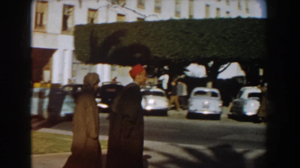 Casablanca street view from 1959 showing two men in traditional clothing near vintage cars and trimmed roadside trees.