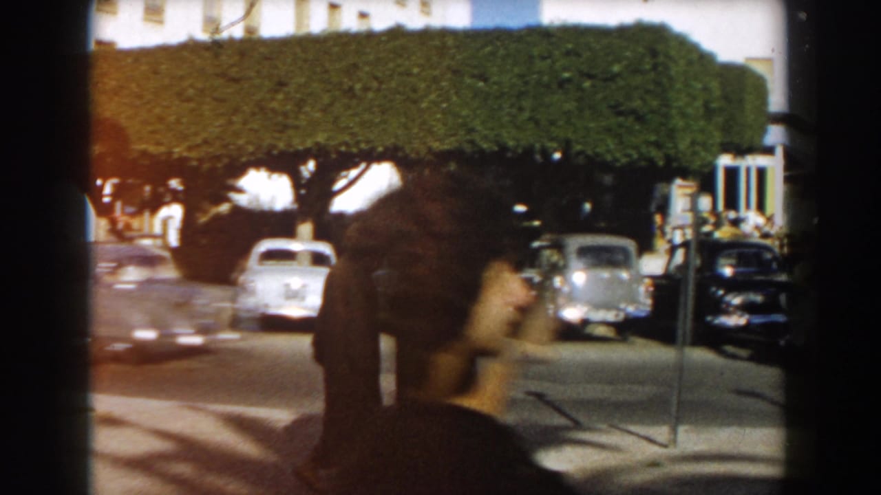 1959 Casablanca street view with rounded cars, manicured trees, sidewalk, and a passing pedestrian close to the camera.