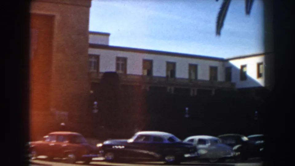 1959 Casablanca street view showing parked cars, a pale multi-story building, and a partial brick facade.