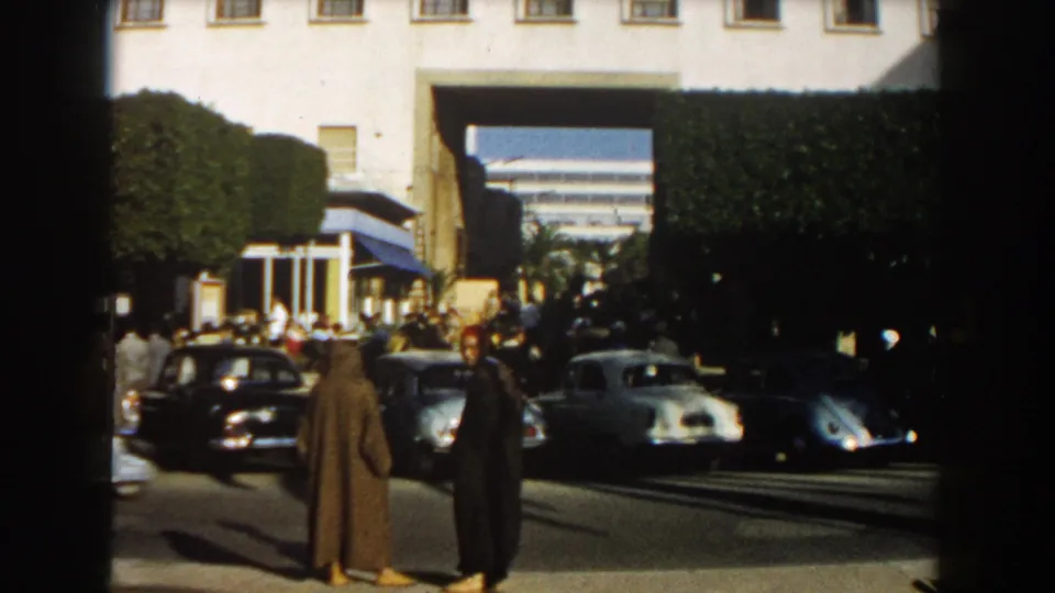 The final frame shows two robed men near a Casablanca curb in 1959, with vintage cars, pedestrians, hedges, and a large building opening visible.