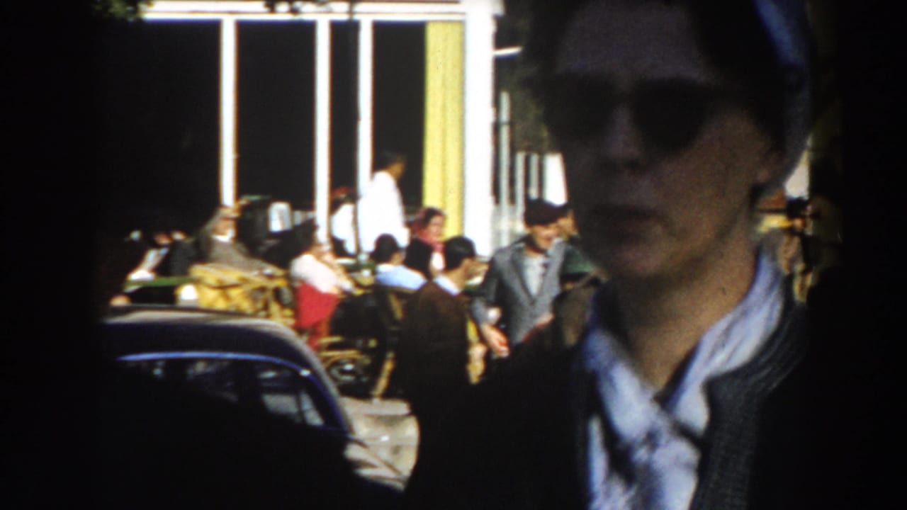 A woman in a headscarf moves past the camera on a busy Casablanca street with parked cars and pedestrians in the background.