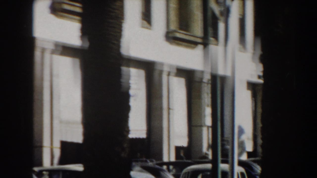 1959 Casablanca street view with a bright white facade, tall palm trunks, and period cars parked at the curb.