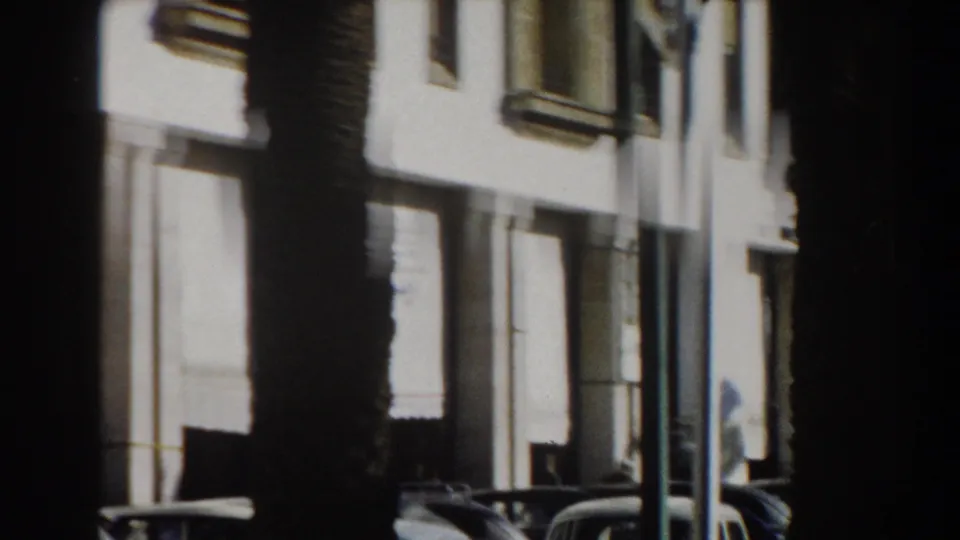 1959 Casablanca street view with a bright white facade, tall palm trunks, and period cars parked at the curb.