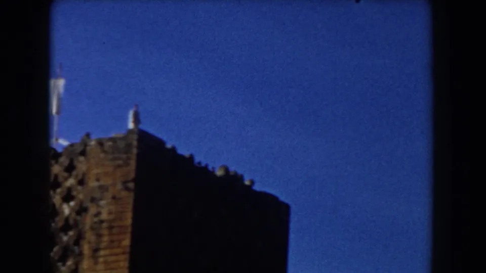 Upward-looking 8mm frame showing a shadowed building corner against a vivid blue sky in Casablanca.