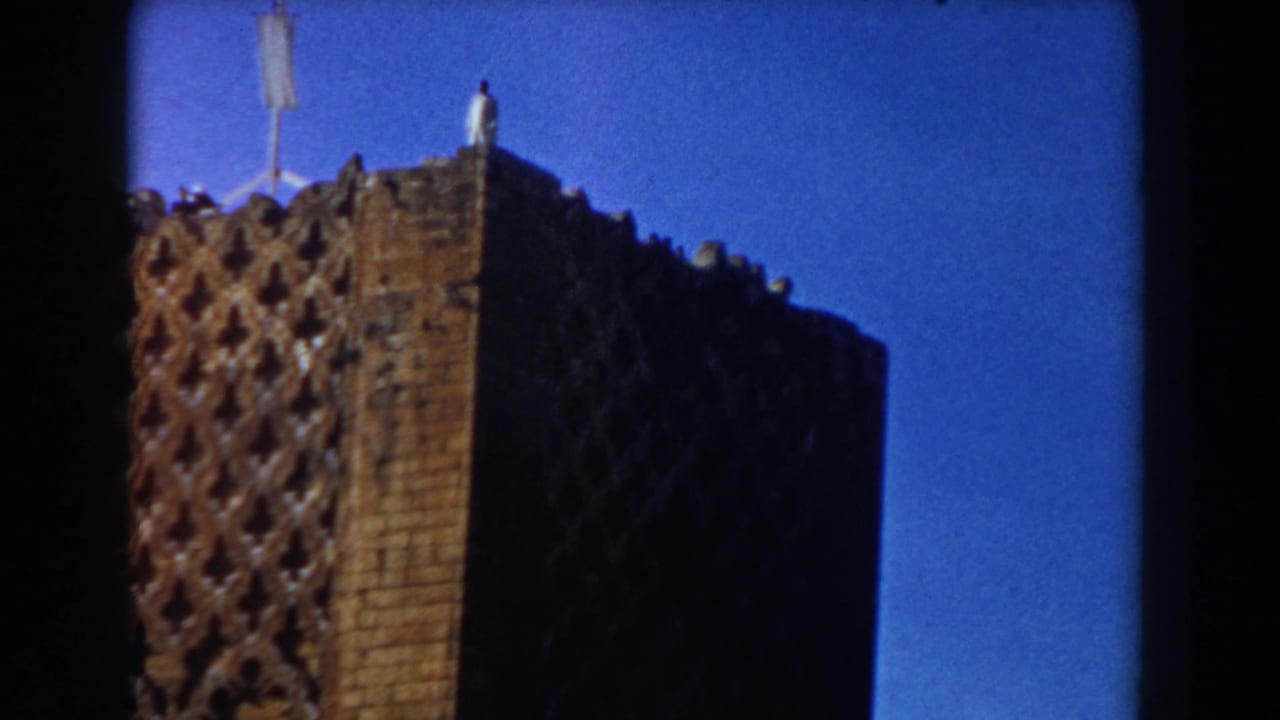 Tall brick tower corner with patterned masonry and roofline details.