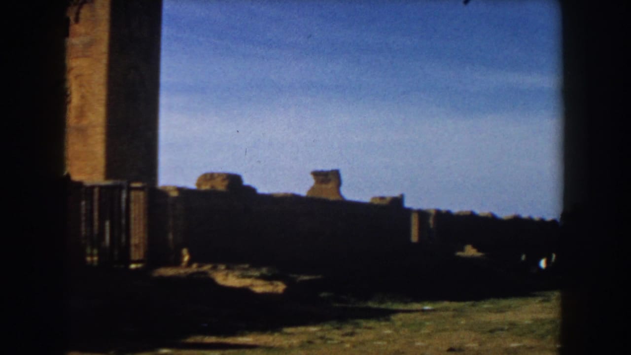1959 Casablanca home-movie frame showing stone ruins and a tall tower seen through a dark foreground edge.