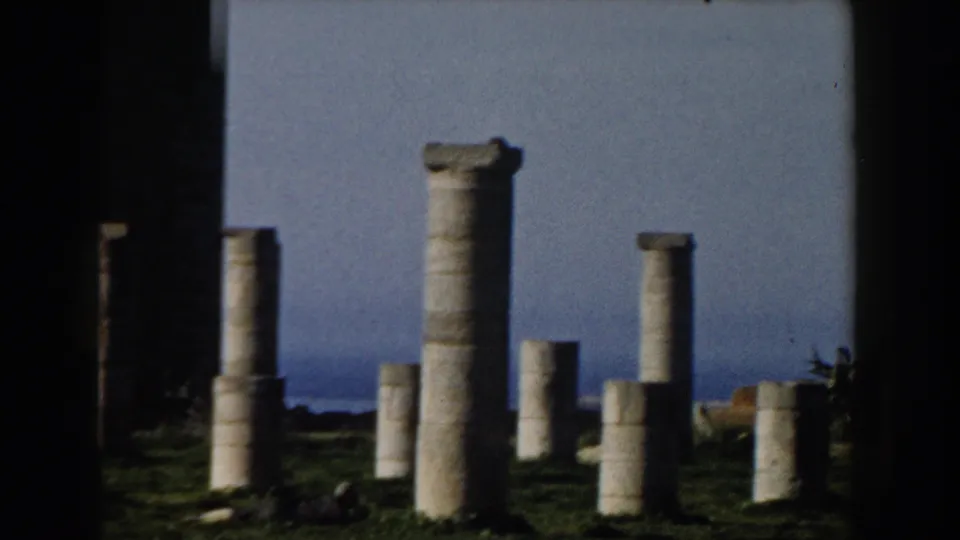 1959 Casablanca frame showing tall and broken stone columns in an open ruin field beneath a pale blue sky.