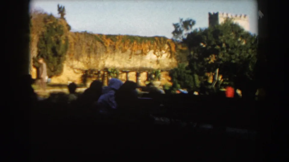 1959 Casablanca garden scene showing dark foreground figures, sunlit masonry, trees, planting, and a distant tower above the wall.